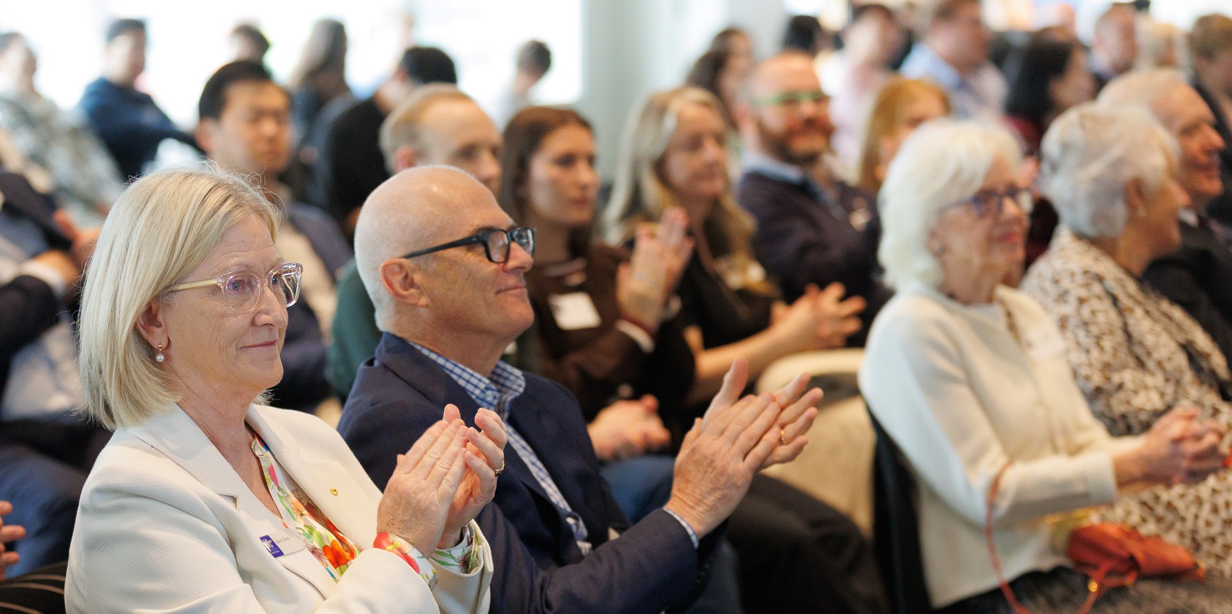 L-R Professor Jane Gunn AO, Professor Mike McGuckin and Mrs Pamela Galli AO clapping in the audience at the Galli Research Symposium.