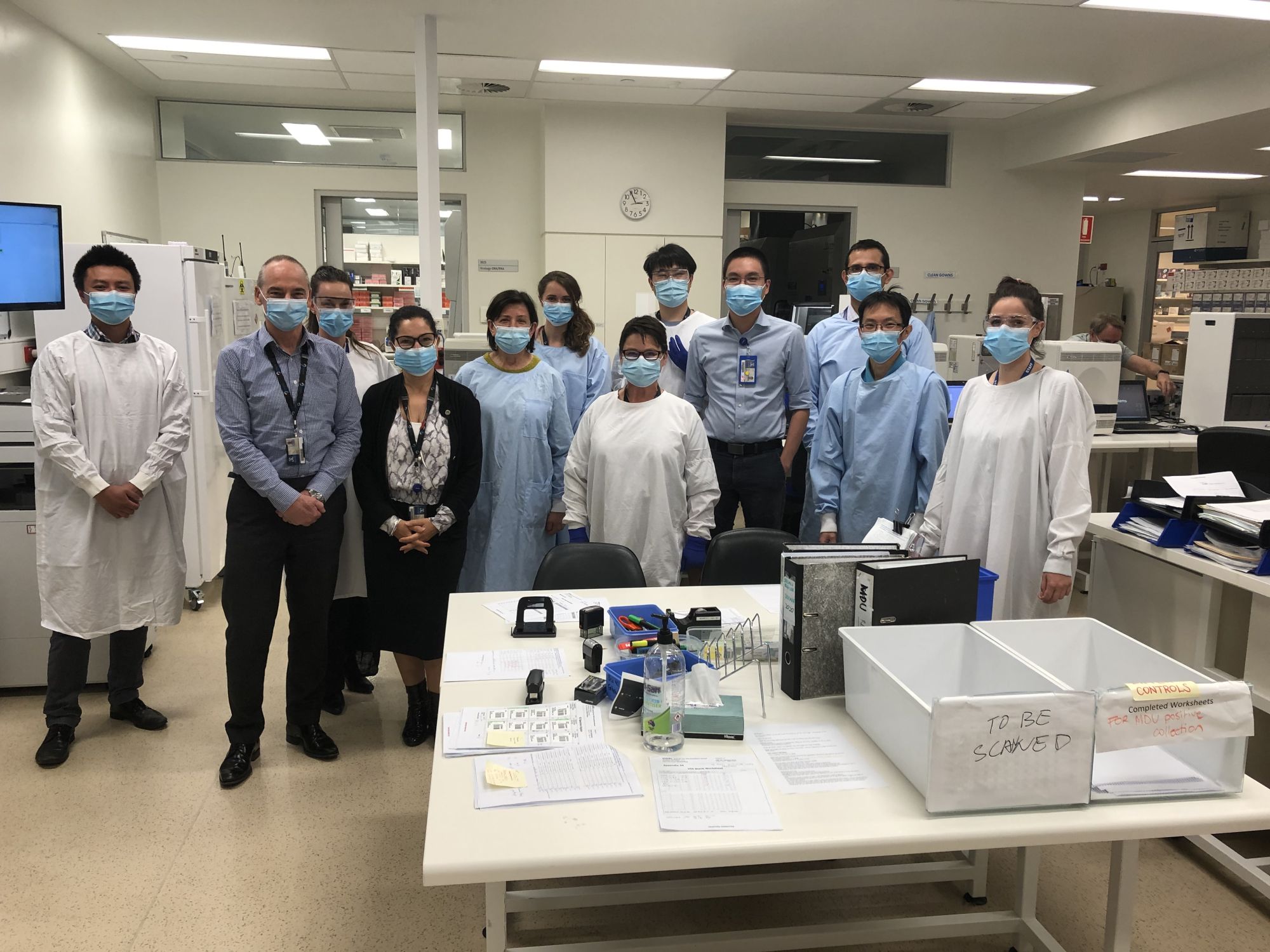 A group of scientists stand together in masks and lab coats.