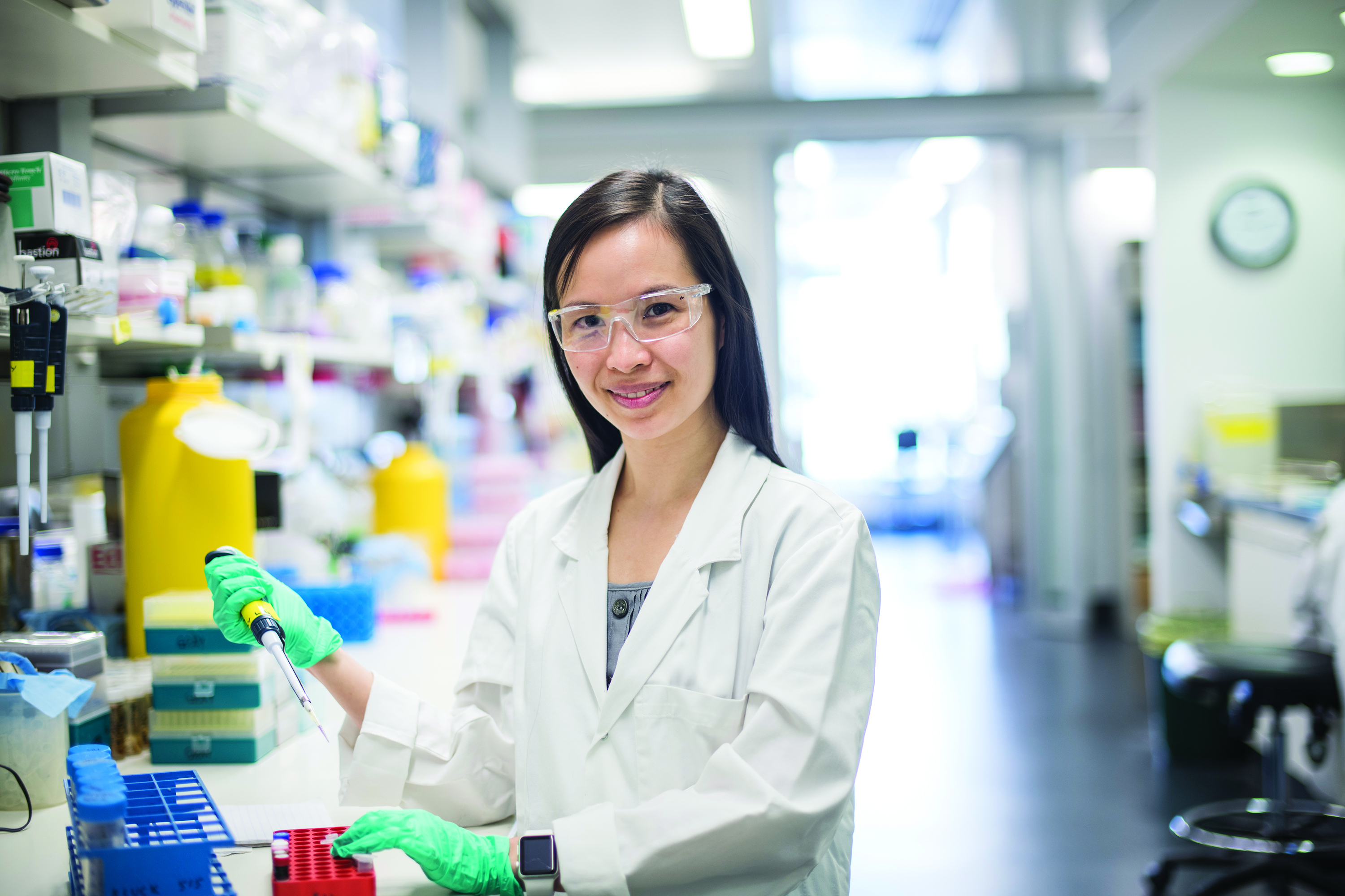 Portrait of Dr Charis Teh, WEHI, inaugural Galli Senior Research Fellow, in a white lab coat holding a pipette in the lab.