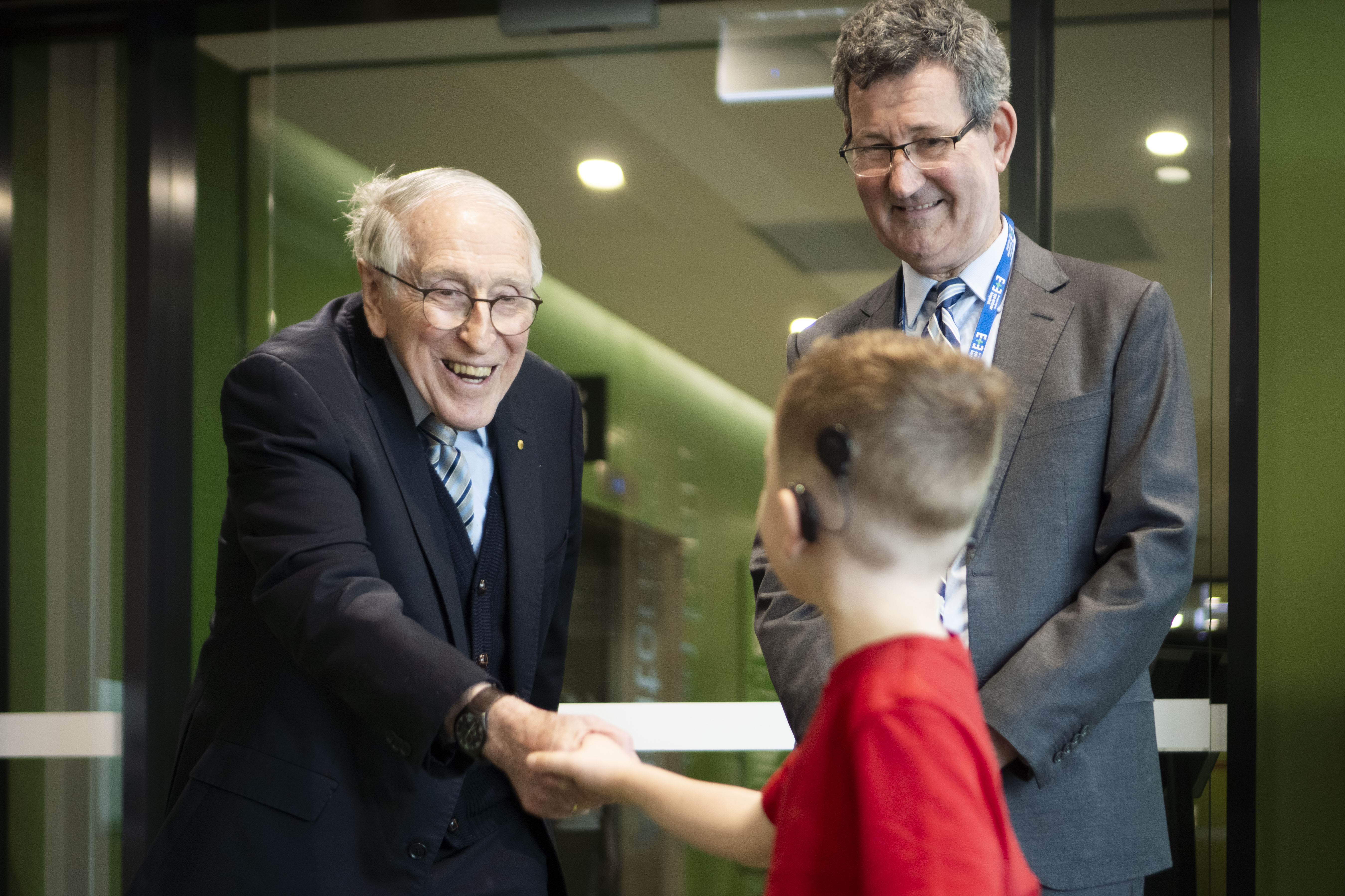Professor Graeme Clark AC shakes hands with six-year-old Hudson, a bilateral cochlear implant recipient who shares the same birthday with Professor Clark, at The Royal Victorian Eye and Ear Hospital.
