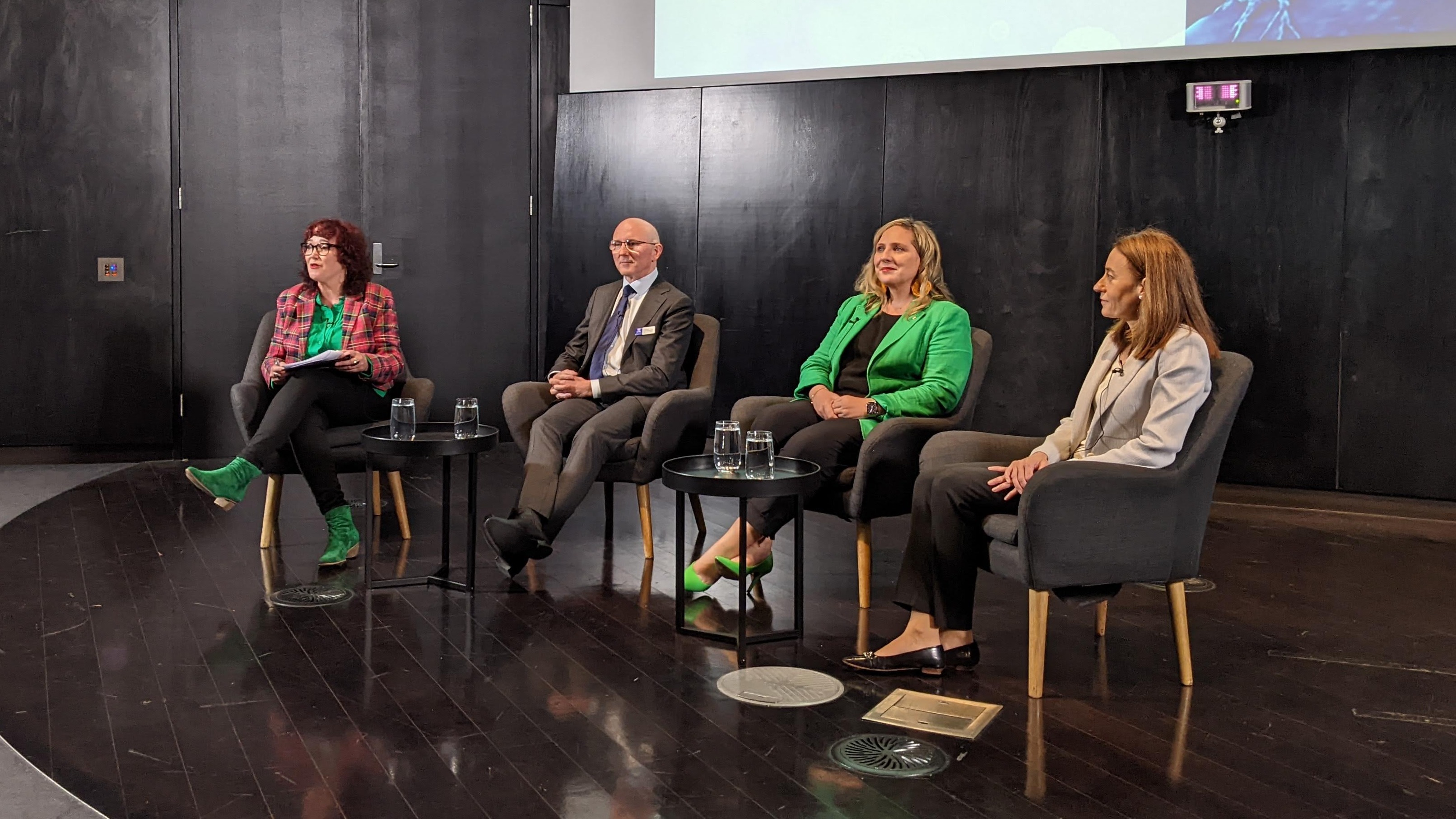 Panellists sitting on chairs on a stage in front of an audience to discuss precision cancer care. From left to right, moderator and ABC journalist, Natasha Mitchell, Professor Sean Grimmond, University Centre for Cancer Research, Misty Jenkins from the Walter and Eliza Hall Institute and Sarah-Jane Dawson, Peter MacCallum Cancer Centre. 