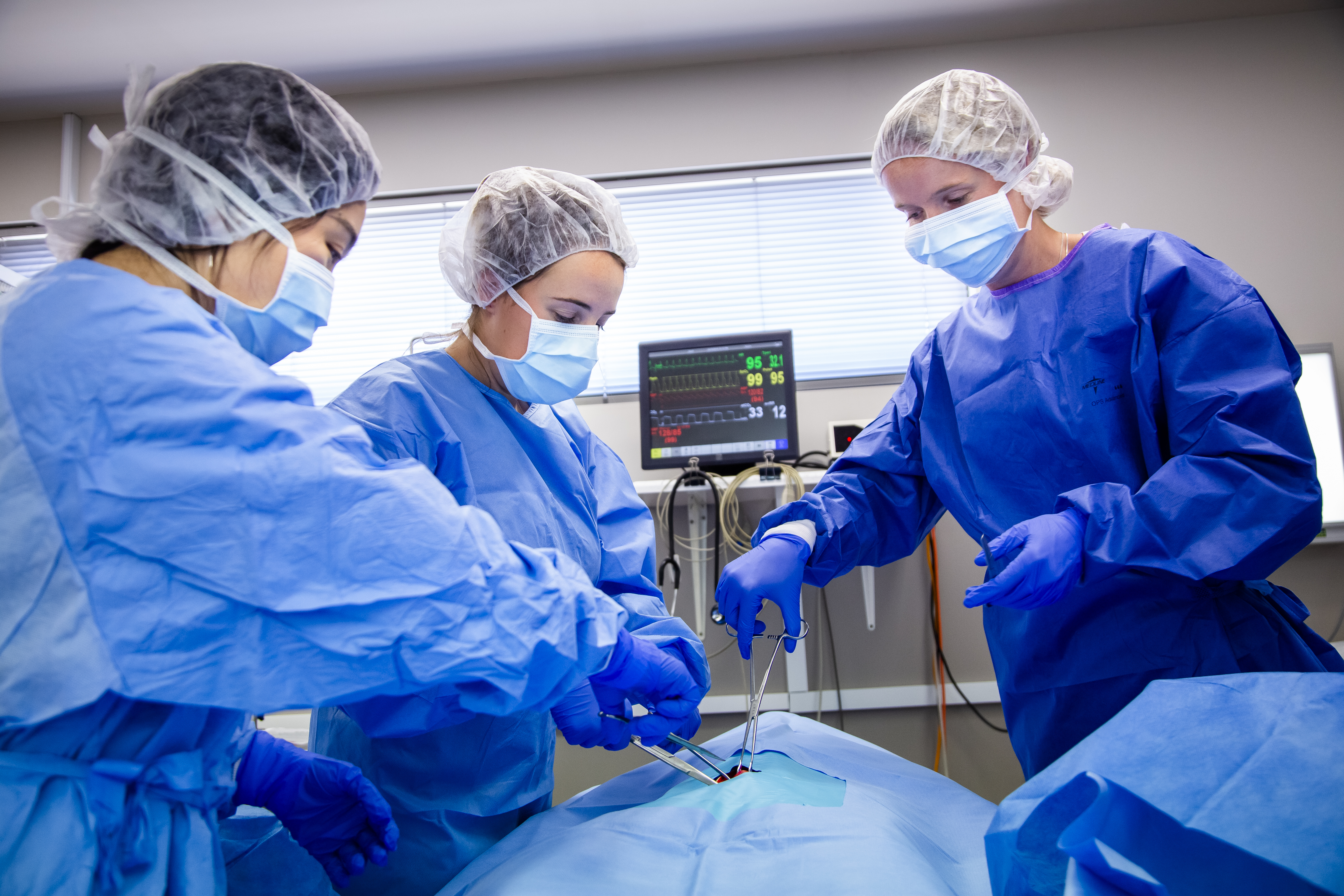 A group of students dressed in scrubs and PPE perform a surgical simulation at the Rural Clinical School in Shepparton.