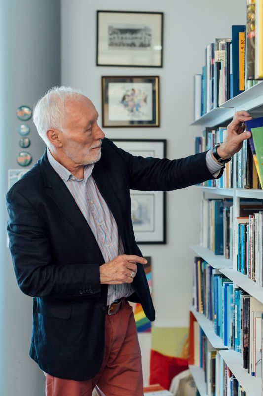 Professor Patrick McGorry AO takes a book out of the bookcase in his office.