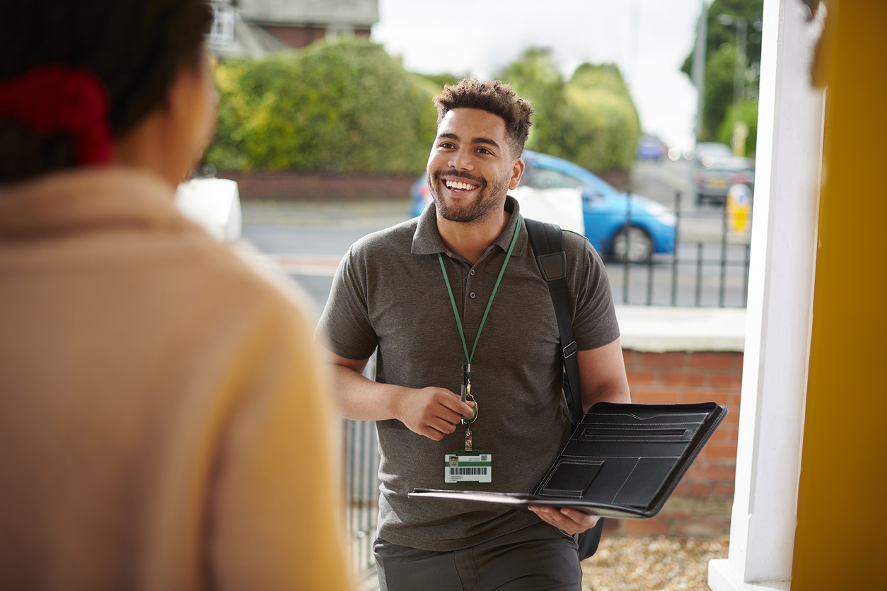 Community worker smiling at resident in home 