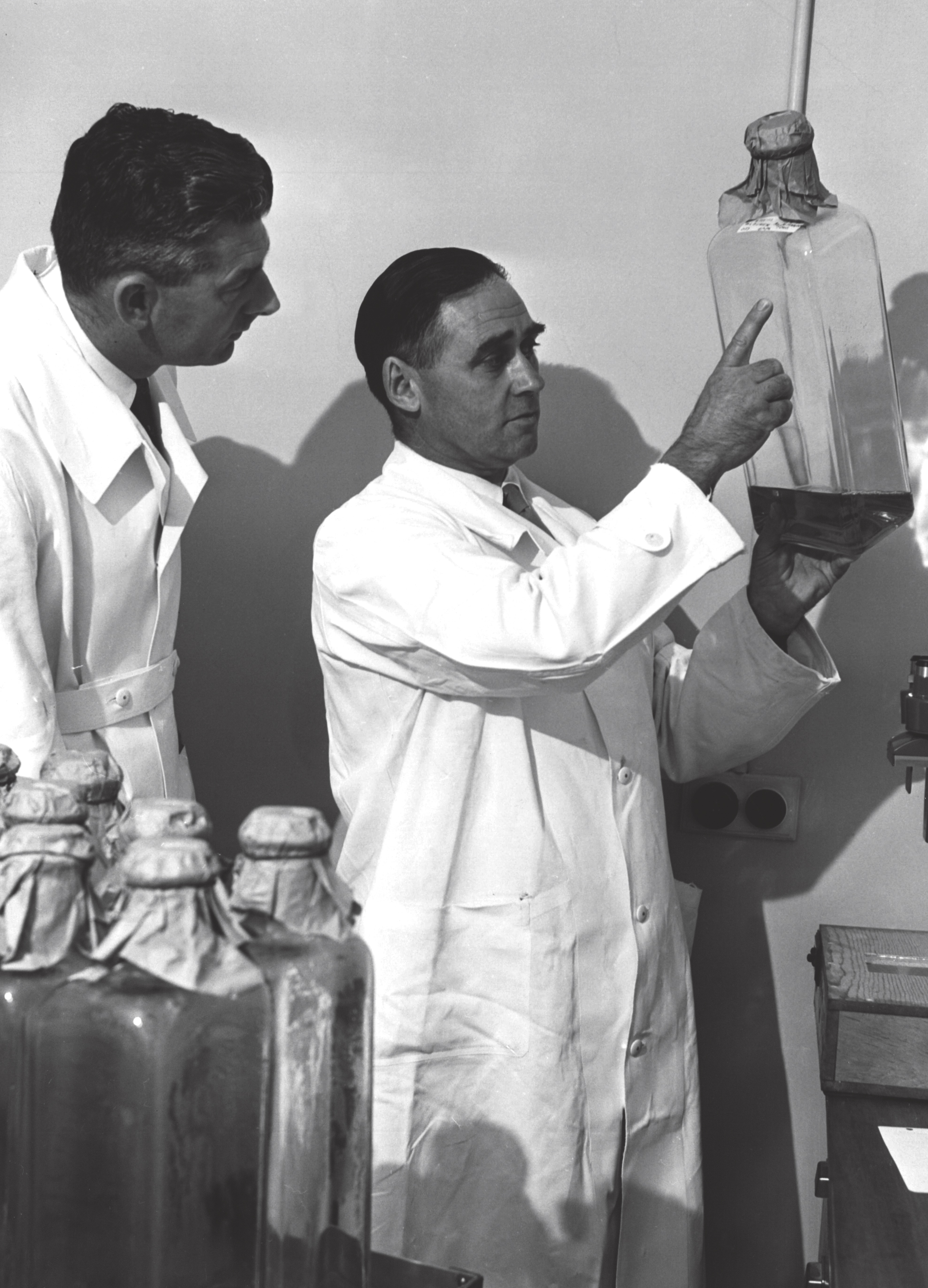 Dr Val Bazeley holding a bottle of Salk polio vaccine, 1956.