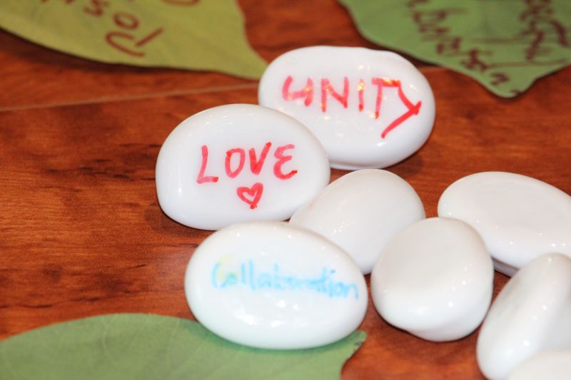Stones and gum leaves with 'Love', 'Unity' and 'Collaboration' written on them.
