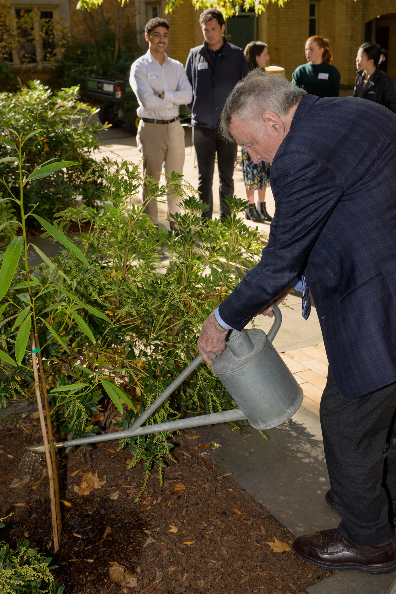 Dr Ron Rosanove watering a tree